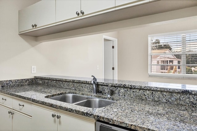 kitchen featuring white cabinetry, stone countertops, and sink