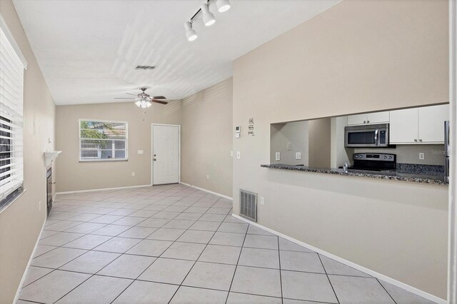 kitchen with ceiling fan, vaulted ceiling, light tile patterned floors, stainless steel appliances, and white cabinets