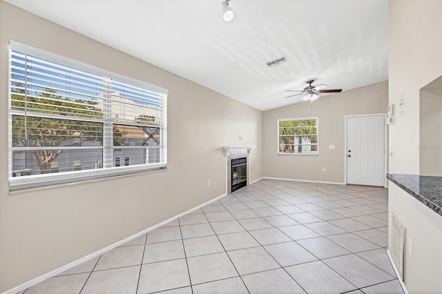 unfurnished living room featuring ceiling fan, light tile patterned floors, and vaulted ceiling