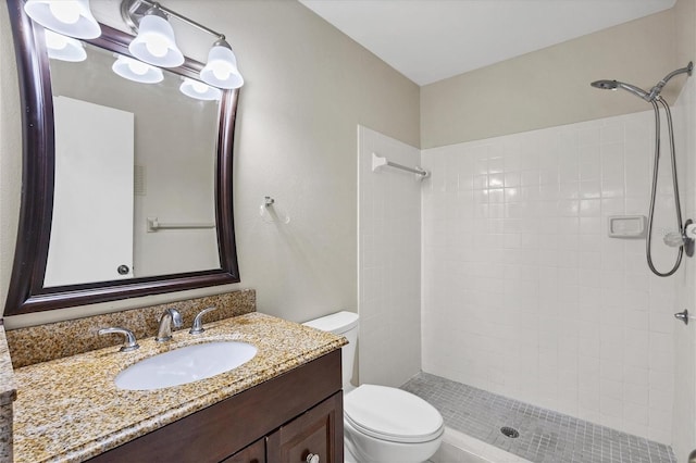 bathroom featuring toilet, a tile shower, and vanity