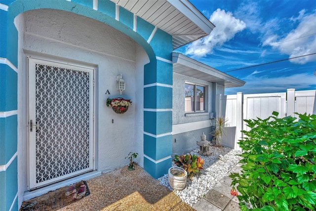 property entrance featuring stucco siding and fence