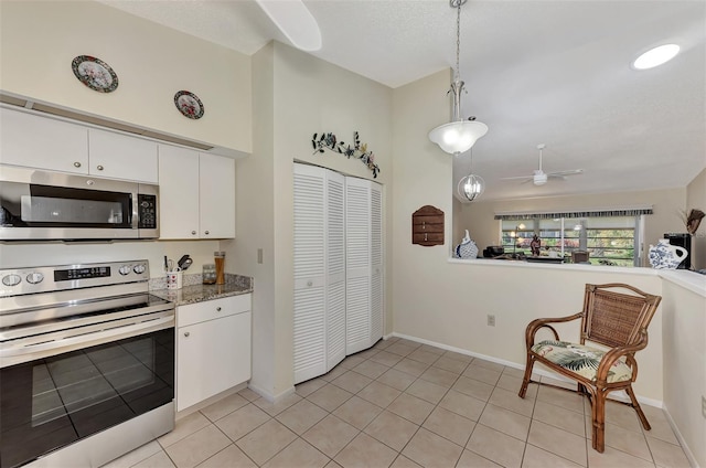 kitchen featuring light tile patterned flooring, white cabinets, ceiling fan, stainless steel appliances, and decorative light fixtures