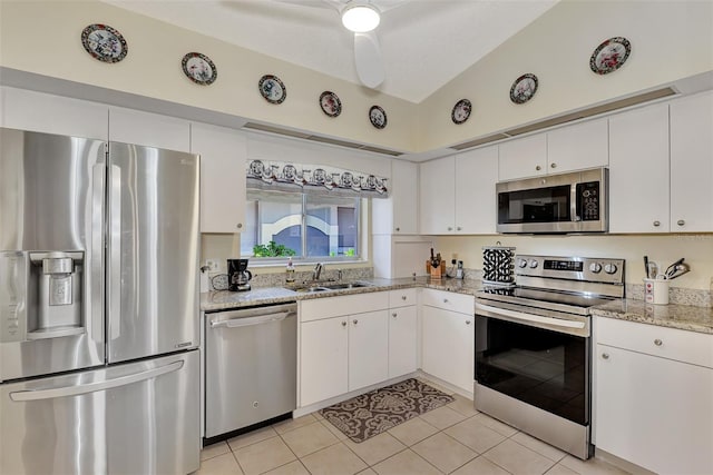 kitchen with stainless steel appliances, vaulted ceiling, light stone counters, white cabinetry, and ceiling fan