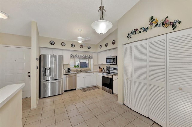 kitchen with pendant lighting, white cabinets, appliances with stainless steel finishes, lofted ceiling, and light tile patterned floors