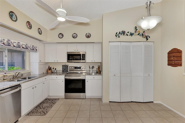 kitchen with light tile patterned flooring, white cabinetry, ceiling fan, stainless steel appliances, and sink