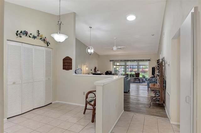 kitchen featuring lofted ceiling, light hardwood / wood-style flooring, kitchen peninsula, ceiling fan, and pendant lighting