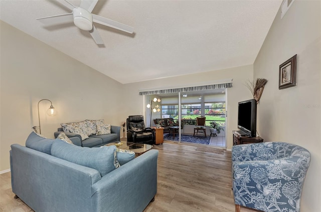 living room with a textured ceiling, ceiling fan, wood-type flooring, and vaulted ceiling