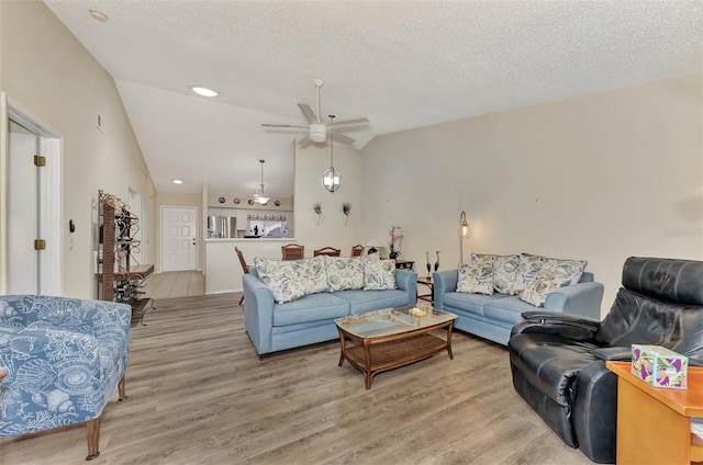 living room featuring wood-type flooring, ceiling fan, lofted ceiling, and a textured ceiling