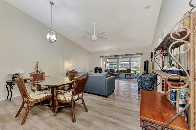 dining room with ceiling fan with notable chandelier, wood-type flooring, and vaulted ceiling