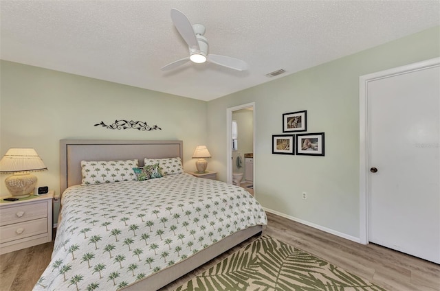 bedroom with wood-type flooring, a textured ceiling, ensuite bath, and ceiling fan