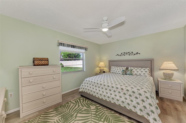 bedroom with light wood-type flooring, ceiling fan, and a textured ceiling