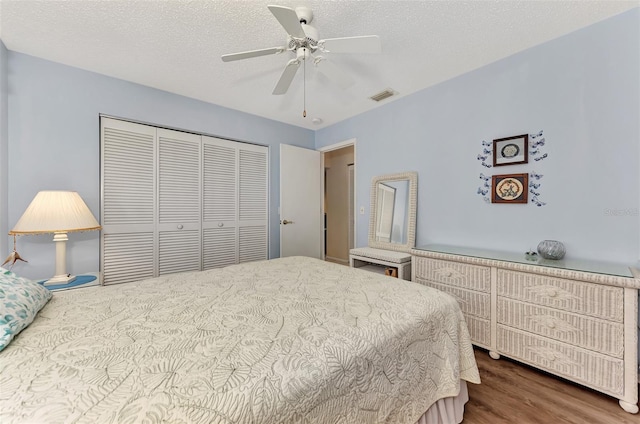 bedroom featuring wood-type flooring, a textured ceiling, a closet, and ceiling fan