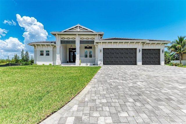 view of front of home with covered porch, a garage, and a front yard