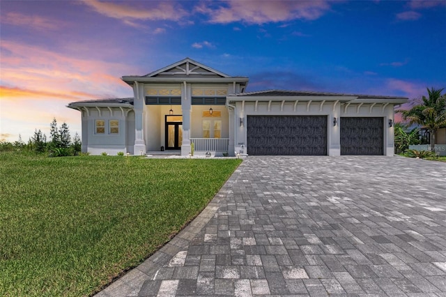 view of front of house with a lawn, a porch, and a garage