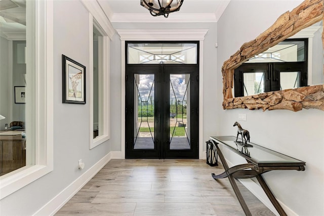 entryway with light wood-type flooring, crown molding, and french doors