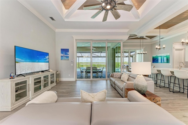 living room with hardwood / wood-style floors, ceiling fan with notable chandelier, and ornamental molding