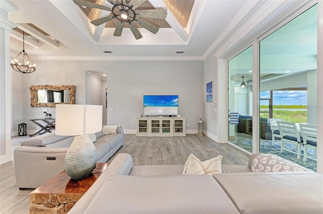 living room featuring ceiling fan with notable chandelier, a tray ceiling, hardwood / wood-style flooring, and ornamental molding