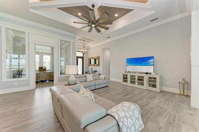 living room featuring ceiling fan with notable chandelier, light hardwood / wood-style floors, a raised ceiling, and ornamental molding