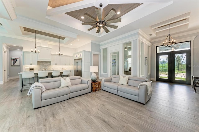 living room featuring french doors, ceiling fan with notable chandelier, light hardwood / wood-style floors, and a raised ceiling