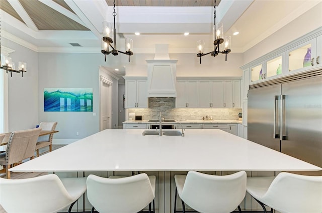 kitchen with a chandelier, a large island with sink, built in refrigerator, and hanging light fixtures