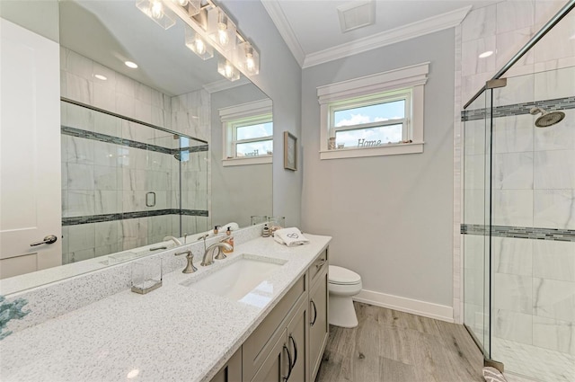 bathroom with ornamental molding, vanity, a shower with door, hardwood / wood-style floors, and toilet