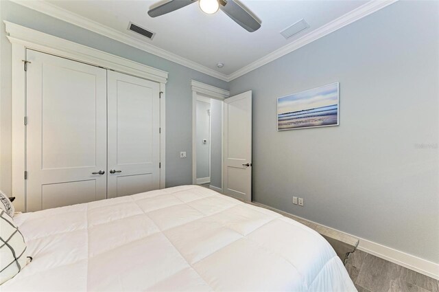 bedroom with wood-type flooring, a closet, ceiling fan, and crown molding