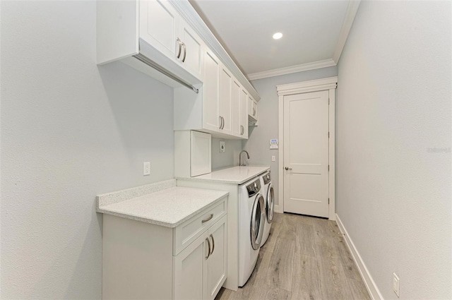 laundry area featuring washing machine and dryer, crown molding, cabinets, and light hardwood / wood-style floors