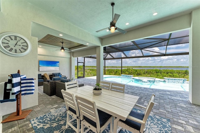 view of patio / terrace featuring a lanai, ceiling fan, an outdoor hangout area, and a pool with hot tub