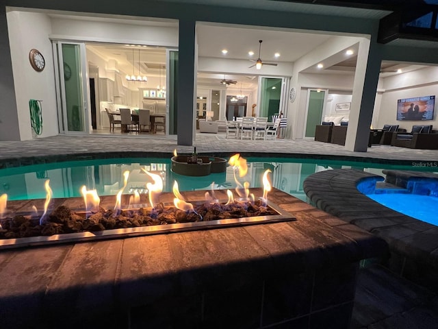 view of swimming pool featuring ceiling fan and a fireplace