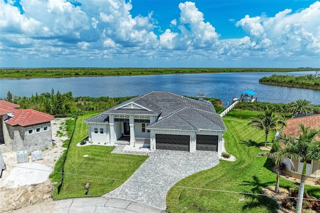 view of front of house with a garage, a water view, and a front lawn