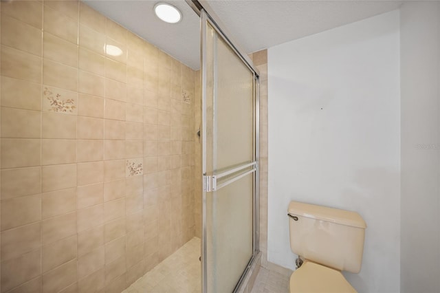 bathroom featuring toilet and a shower with shower door