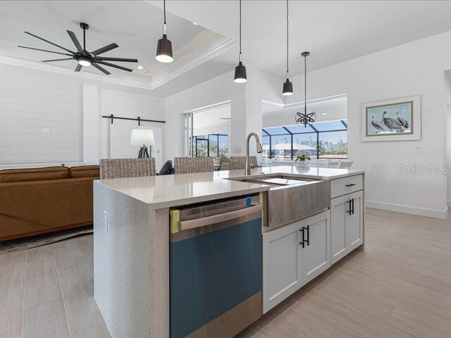 kitchen with a barn door, dishwashing machine, open floor plan, a tray ceiling, and a sink