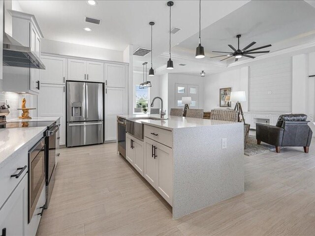 kitchen with visible vents, hanging light fixtures, appliances with stainless steel finishes, open floor plan, and wall chimney exhaust hood