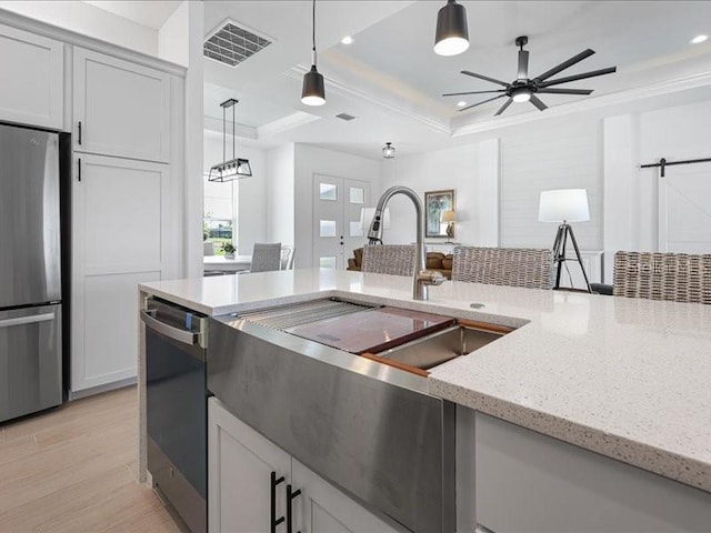 kitchen featuring stainless steel appliances, visible vents, ornamental molding, a raised ceiling, and pendant lighting