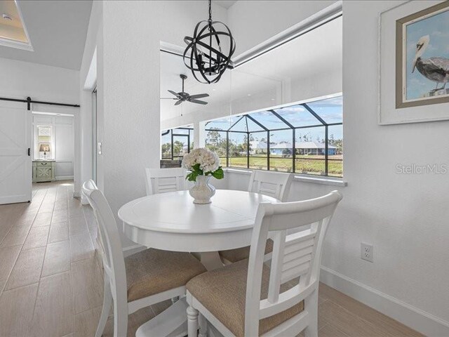 dining area with a wealth of natural light, a sunroom, baseboards, and a barn door