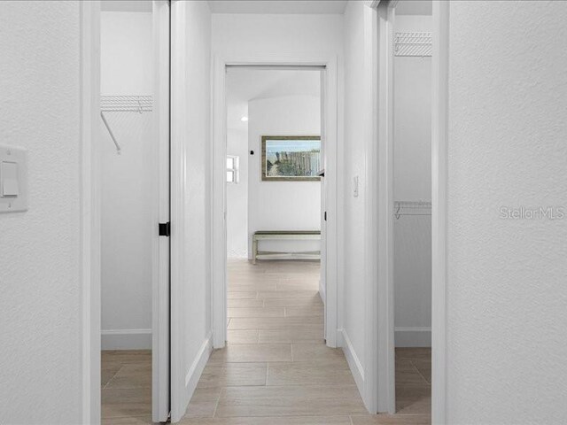 hallway featuring a textured wall and wood finish floors