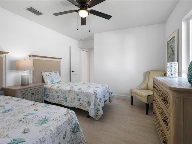 bedroom featuring ceiling fan, wood finished floors, visible vents, and baseboards