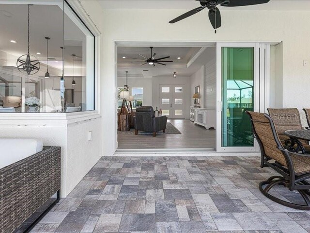 sunroom featuring a raised ceiling and ceiling fan