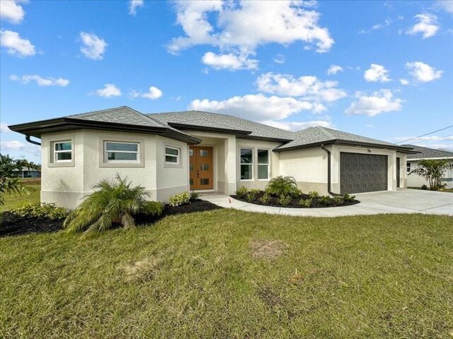 prairie-style house featuring an attached garage, stucco siding, concrete driveway, and a front yard