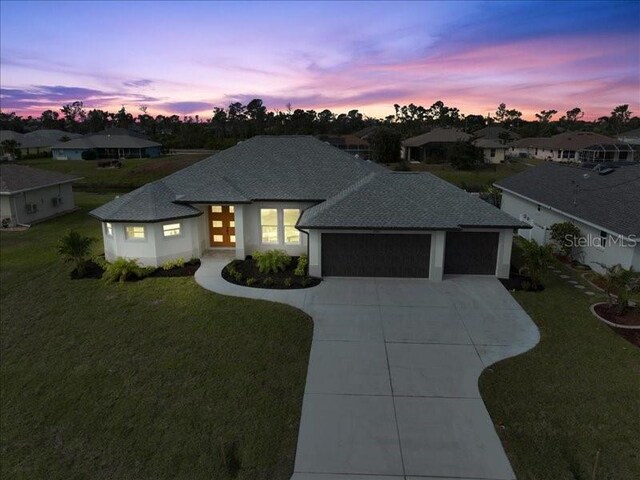 view of front of home with a garage, concrete driveway, a shingled roof, and a front lawn