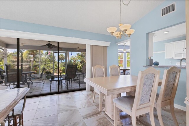 dining area featuring ceiling fan with notable chandelier and vaulted ceiling