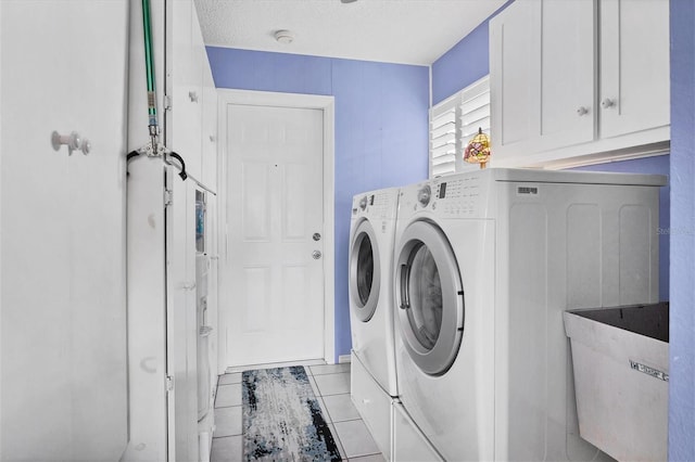 laundry room featuring light tile patterned floors, sink, washing machine and dryer, cabinets, and a textured ceiling