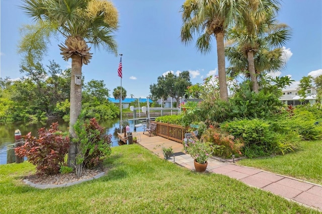 view of property's community with a dock, a lawn, and a water view