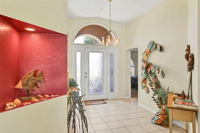 foyer entrance featuring light tile patterned floors, a notable chandelier, and high vaulted ceiling