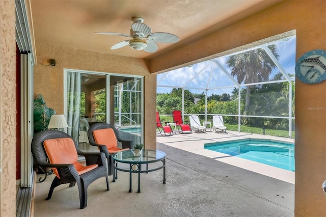 view of pool with a patio, ceiling fan, and glass enclosure