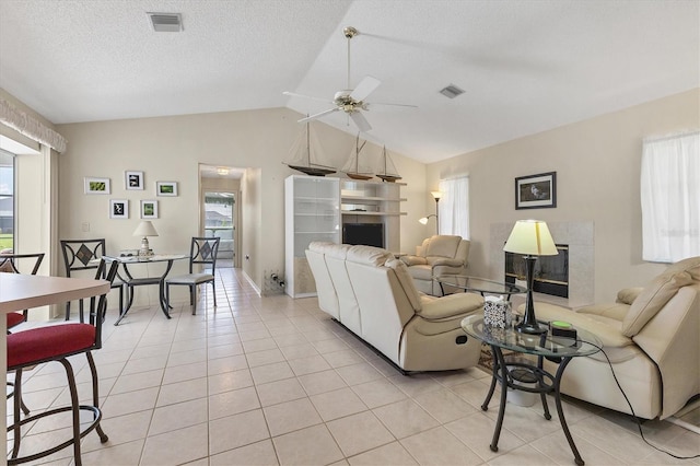 tiled living room with vaulted ceiling, ceiling fan, and a textured ceiling