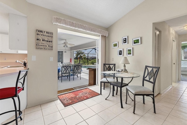 dining space featuring ceiling fan, sink, light tile patterned floors, and a textured ceiling