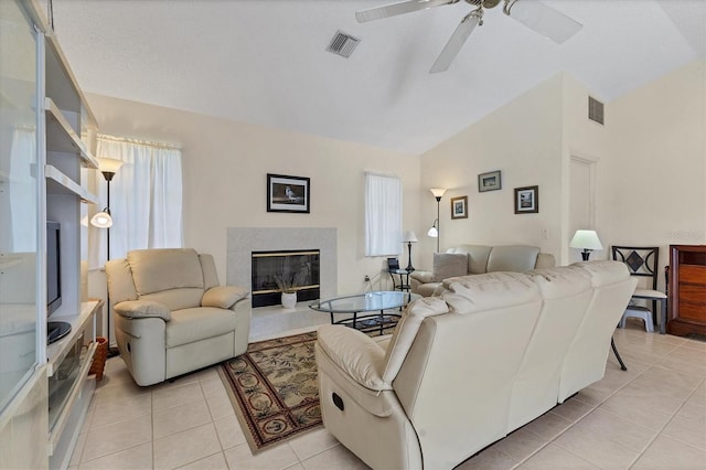 living room with ceiling fan, lofted ceiling, light tile patterned floors, and a fireplace