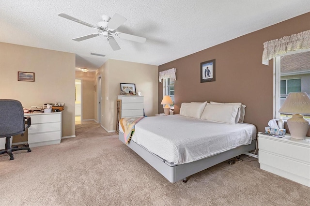 bedroom featuring ceiling fan, light colored carpet, and a textured ceiling