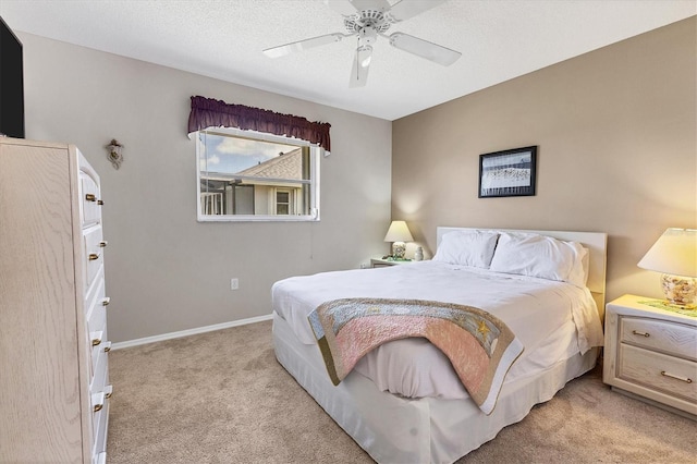 bedroom with a textured ceiling, light colored carpet, and ceiling fan